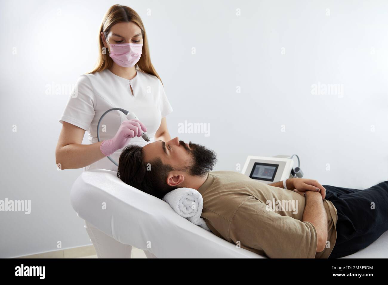 Doctor female dermatologist trichologist makes a procedure to stimulate hair growth on head to a