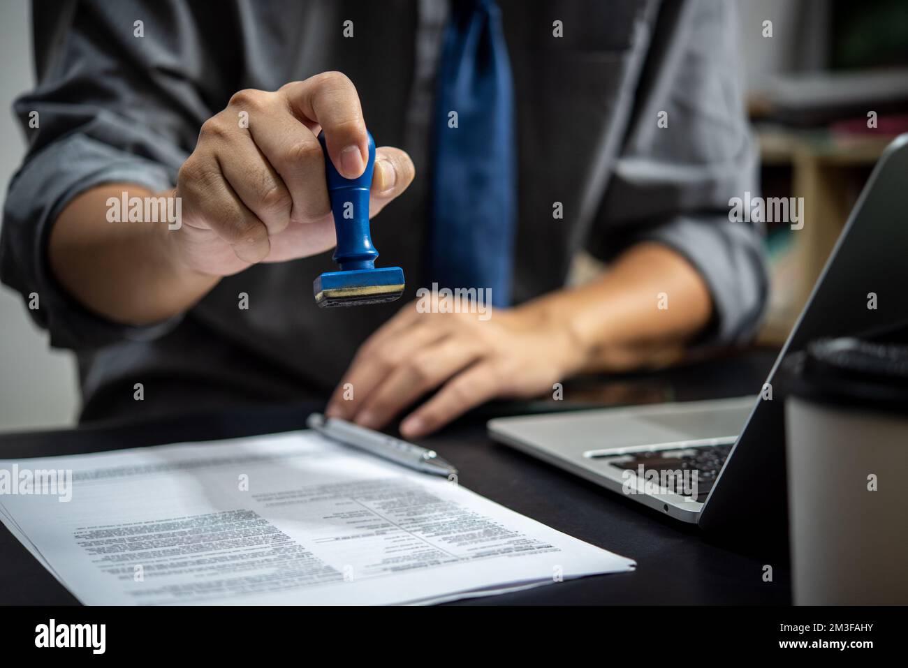 businessman hand stamping approved on certificate document contract in office. Lawyer stamping permit on paperwork at wooden desk. Stock Photo