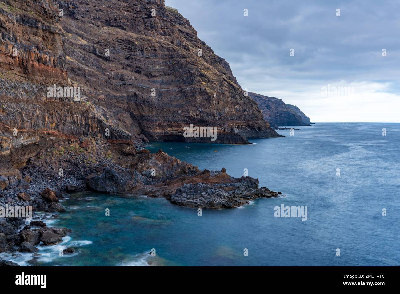 Long exposure silk water on rough extreme volcanic coastline Stock Photo