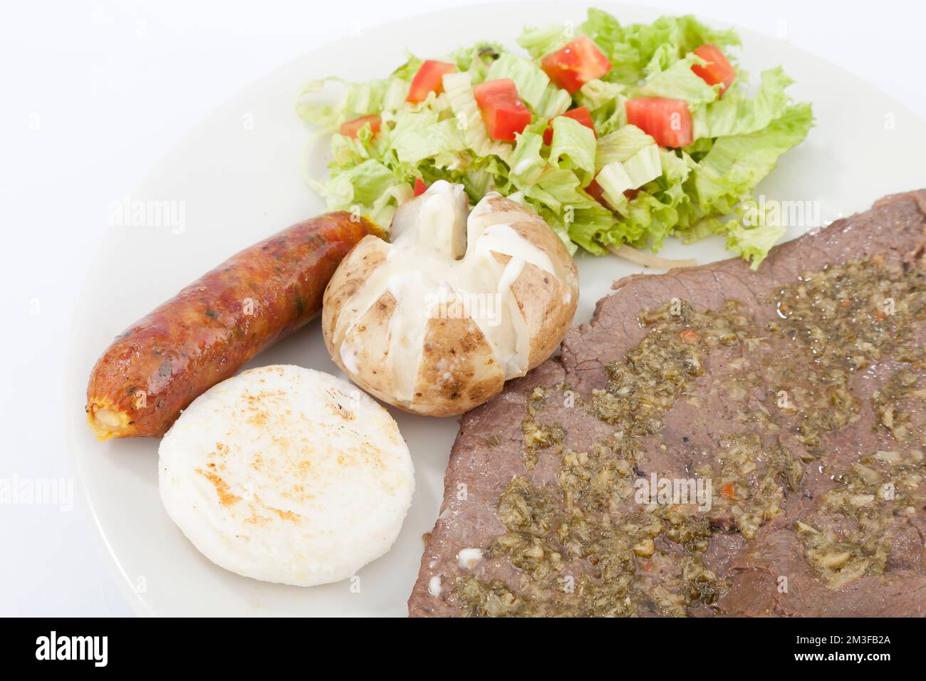 Portion of meat with sausage and corn arepa salad. Stock Photo