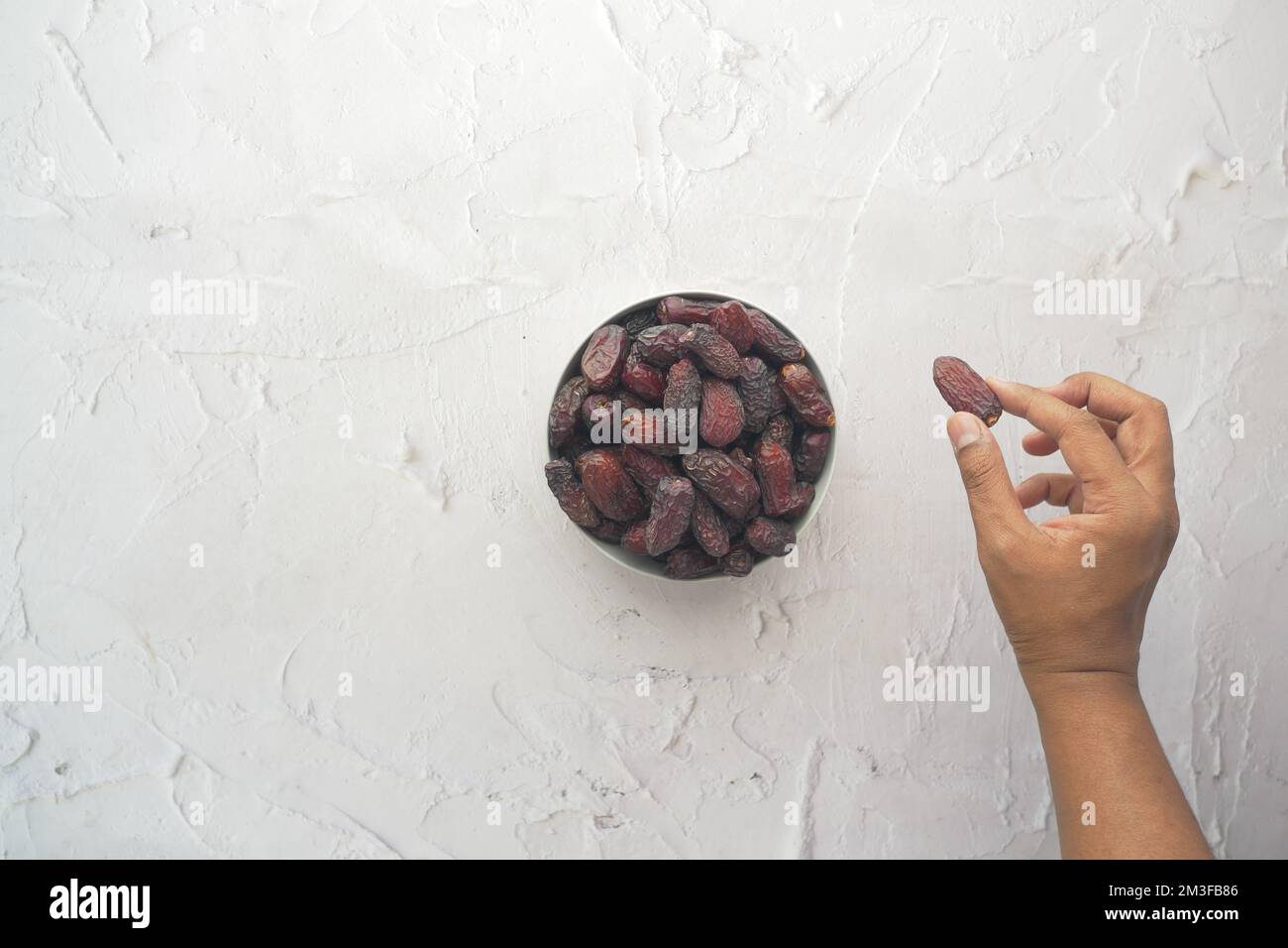 hand pick a dried date fruit from a bowl  Stock Photo