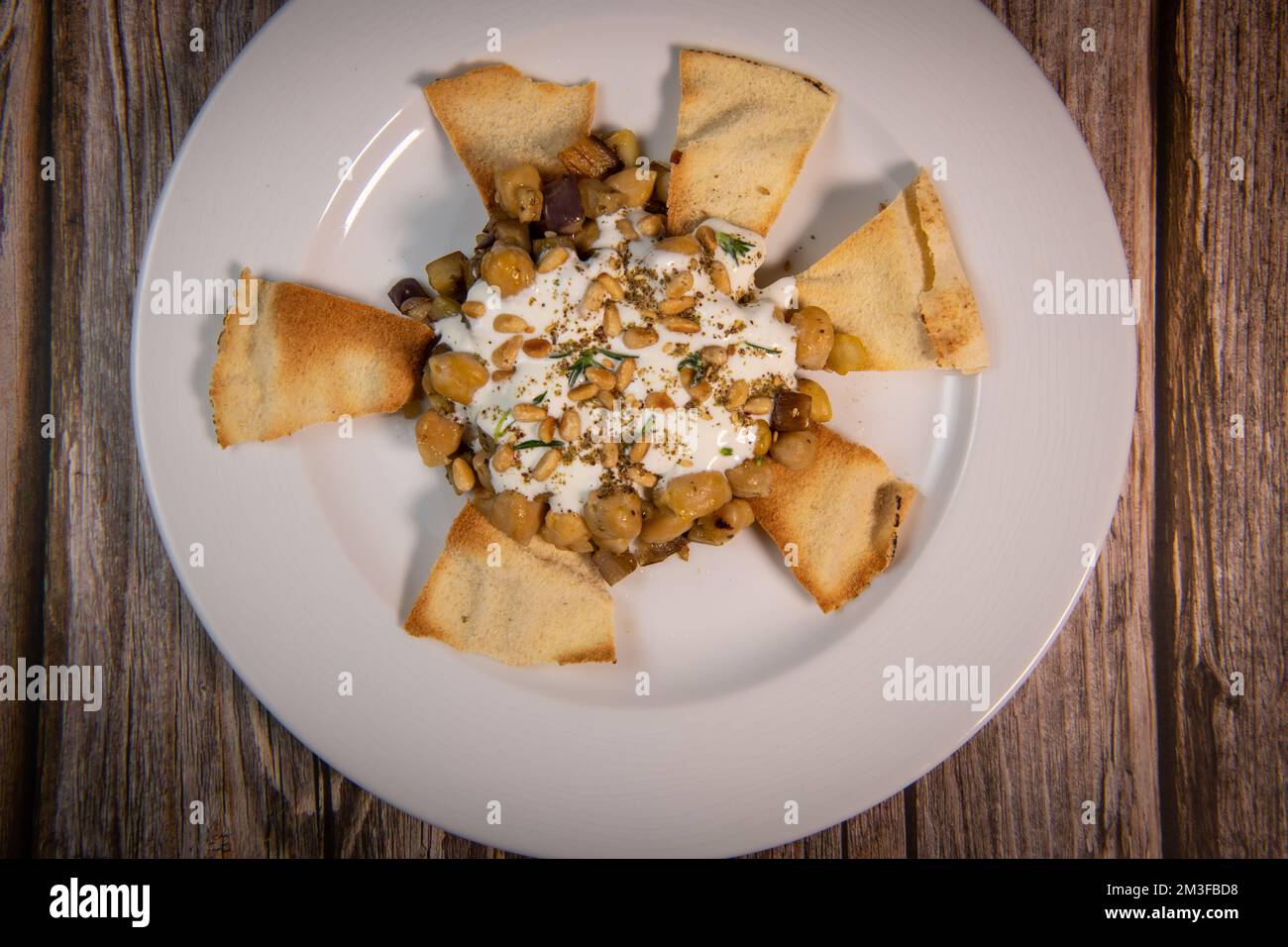 Oriental recipe aubergine and chickpea fatteh, pita, Greek yogurt, roasted pine nuts, zaatar Stock Photo
