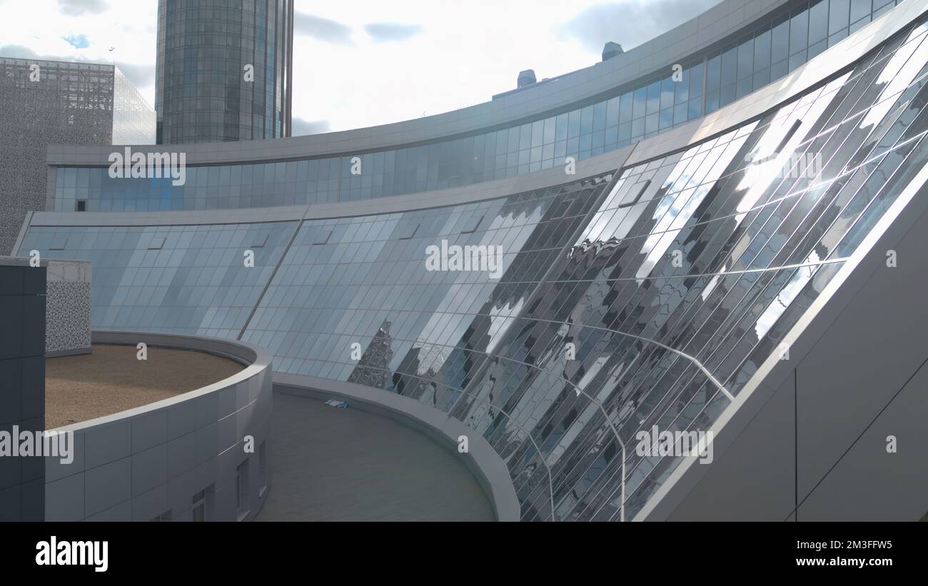 Flying above glass facade building on a blue cloudy sky background. Stock footage. Office building in the city center Stock Photo