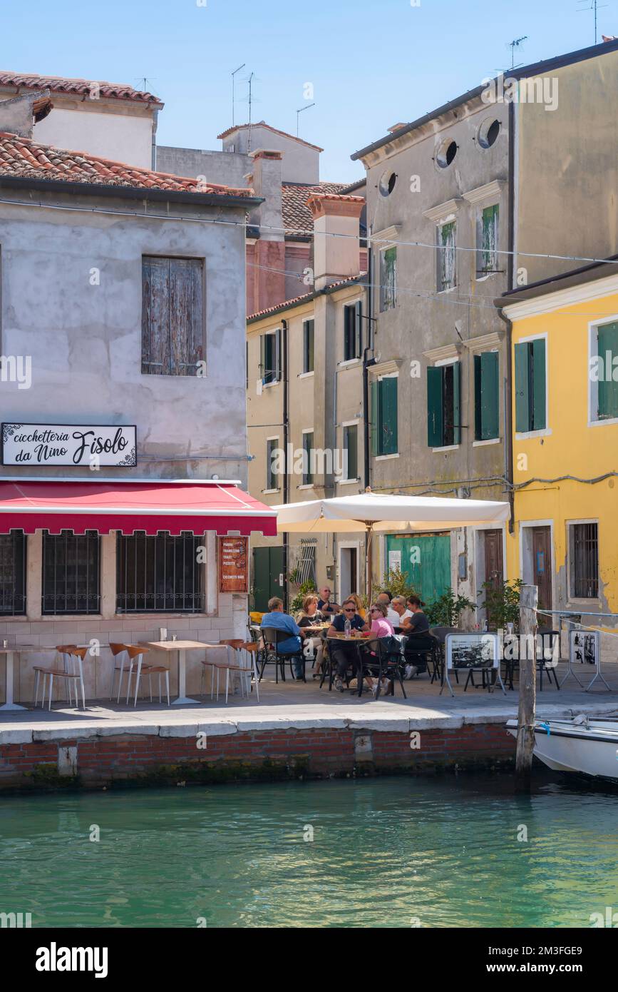 Canal Italy cafe, view in summer of a group of people dining at a cafe terrace beside the Canal Vena in Chioggia, Comune of Venice, Italy Stock Photo