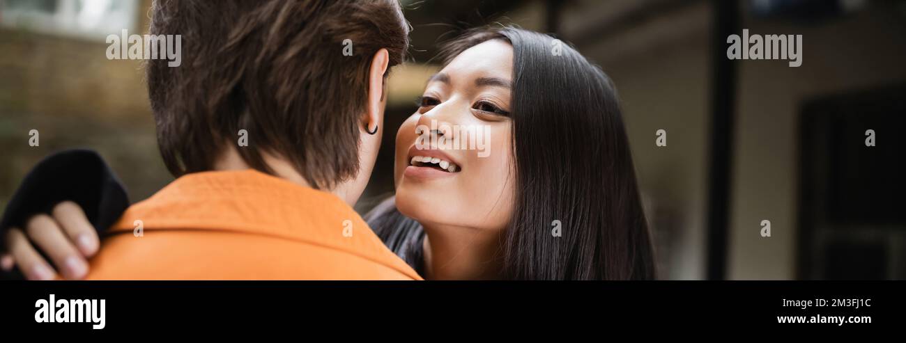 Young asian woman hugging and whispering to boyfriend on terrace of ...