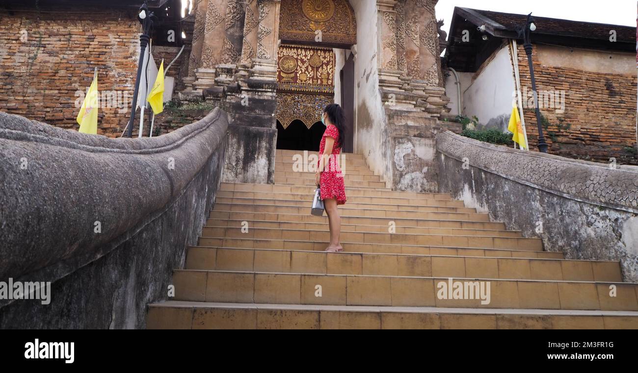 The red dress in a back-facing position with the door to the temple. Stock Photo