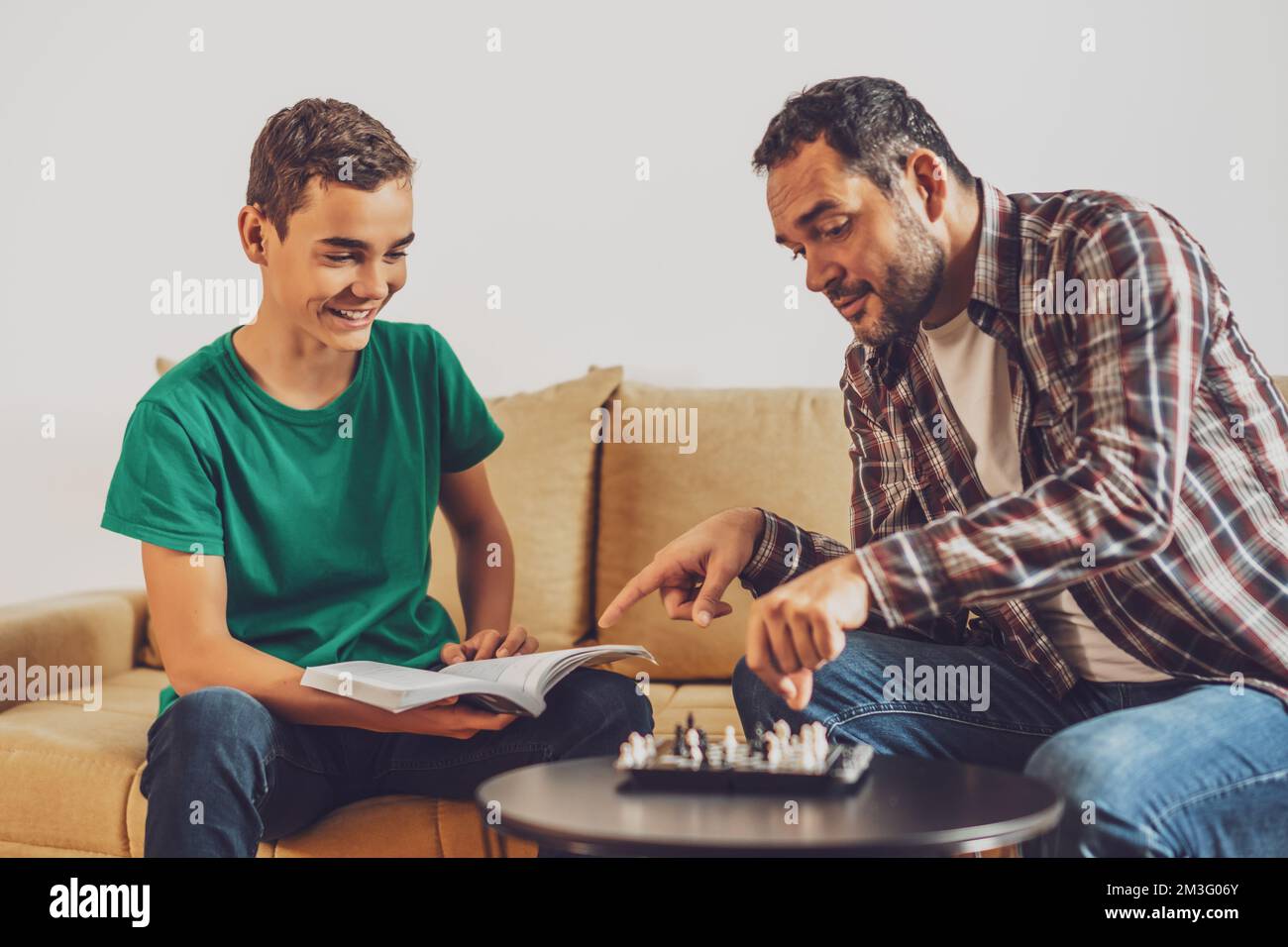 Father and son are playing chess at home. Boy is learning about chess. Stock Photo