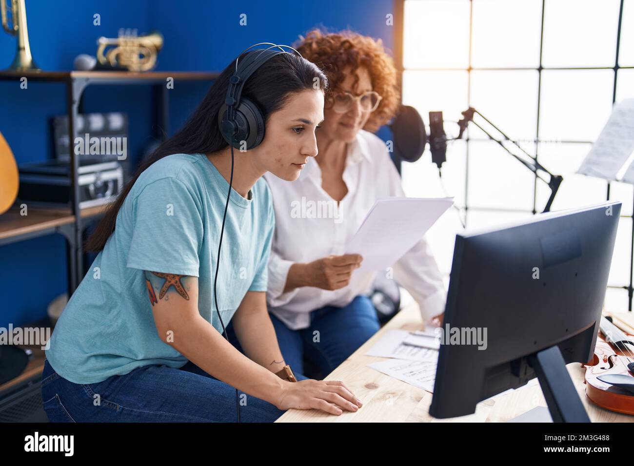 Two women musicians composing song using computer at music studio Stock ...