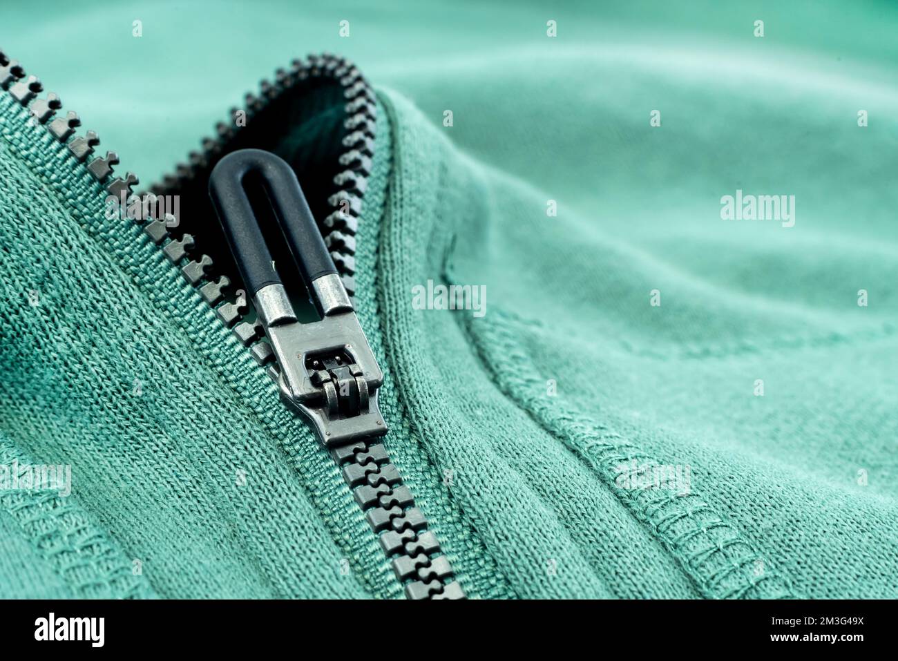 Close-up of the zipper on the green clothing. Zipper with lock. Fabric with zipper Stock Photo