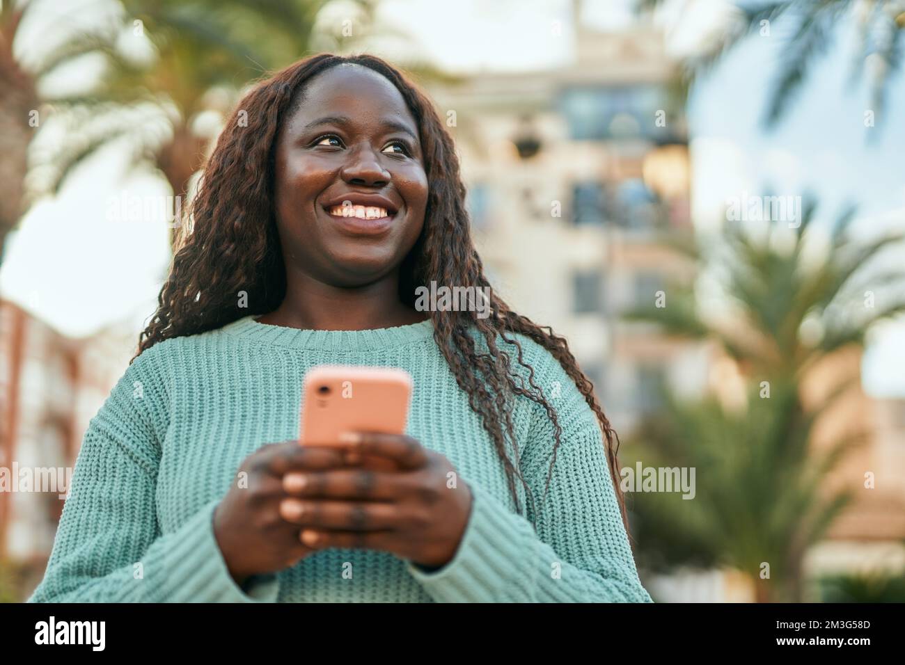 Young african woman smiling happy using smartphone at the city Stock ...