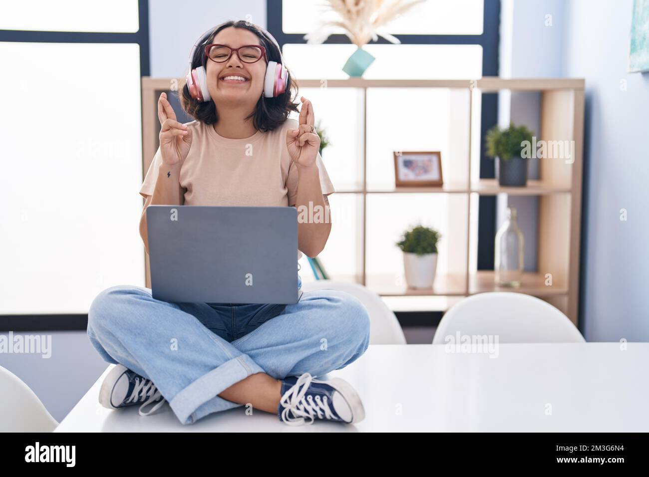 Young hispanic woman using laptop sitting on the table wearing ...