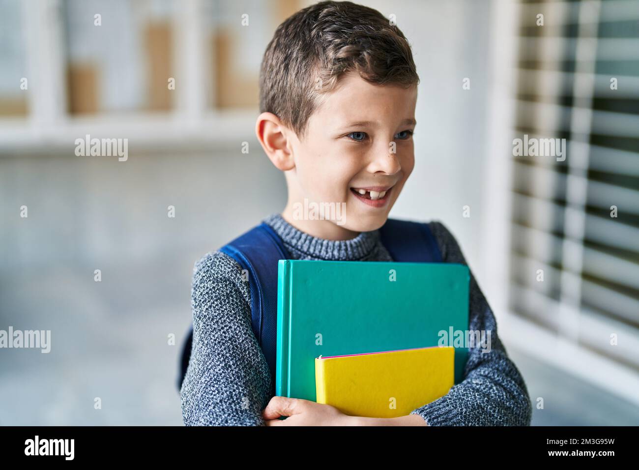 Blond child student holding books standing at school Stock Photo - Alamy