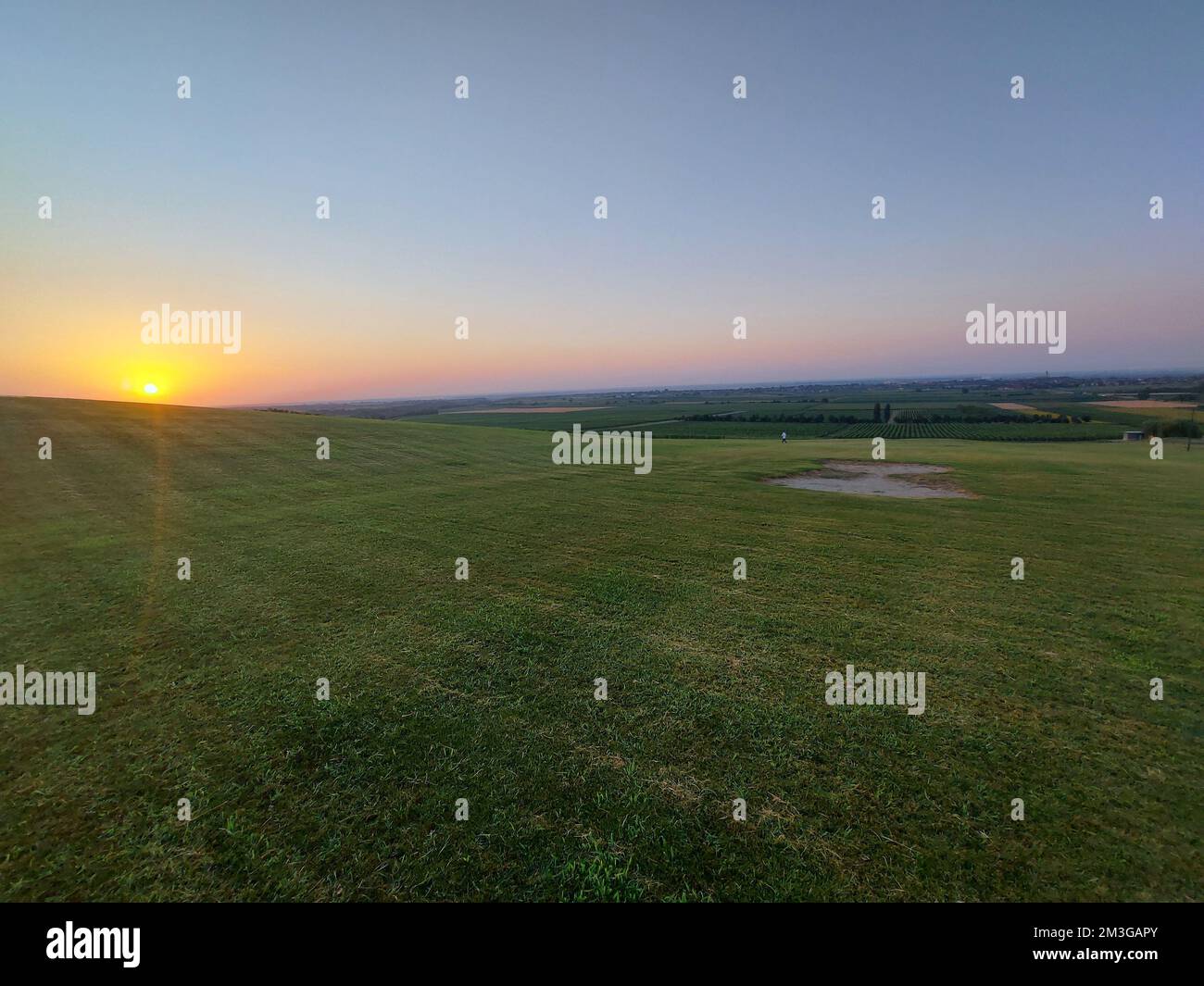 A beautiful landscape of a green field at a calm sunset Stock Photo - Alamy