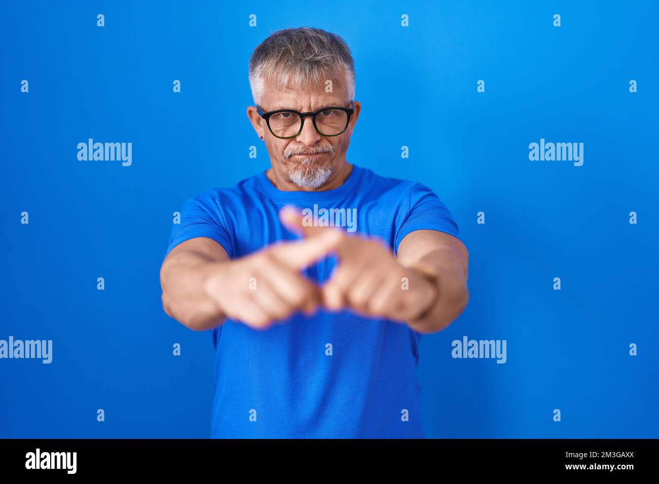Hispanic man with grey hair standing over blue background rejection ...