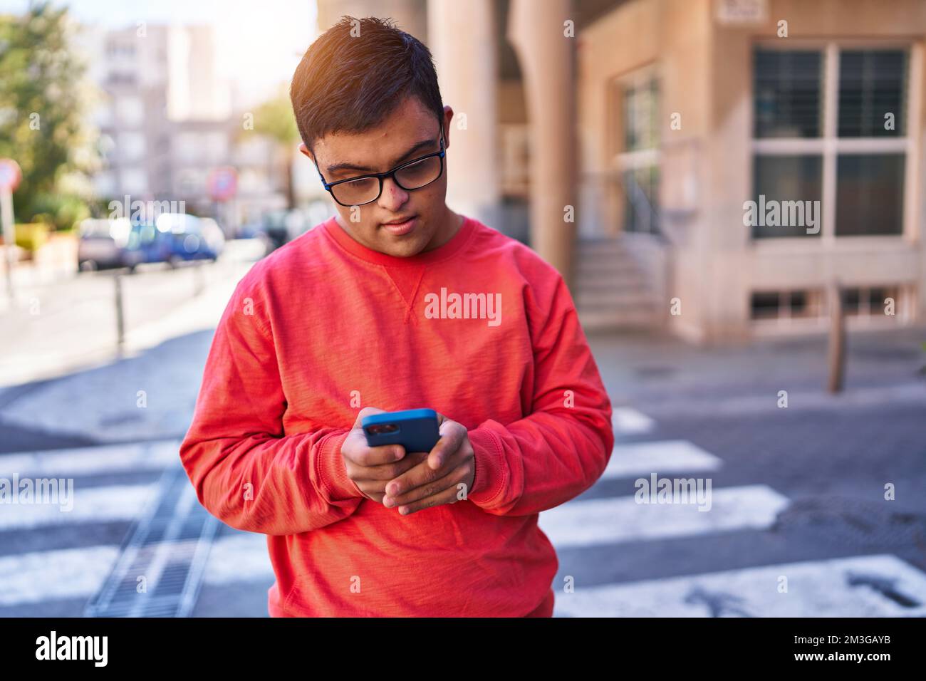 Down syndrome man using smartphone with serious expression at street Stock Photo