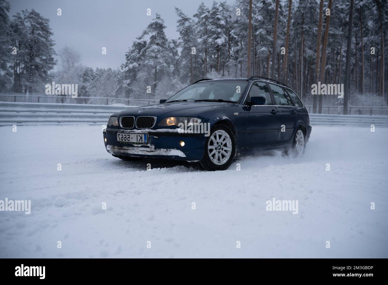12-12-2022 Riga, Latvia  a car is driving through the snow in the woods on a cold day with no one around it and it is covered in snow. . Stock Photo