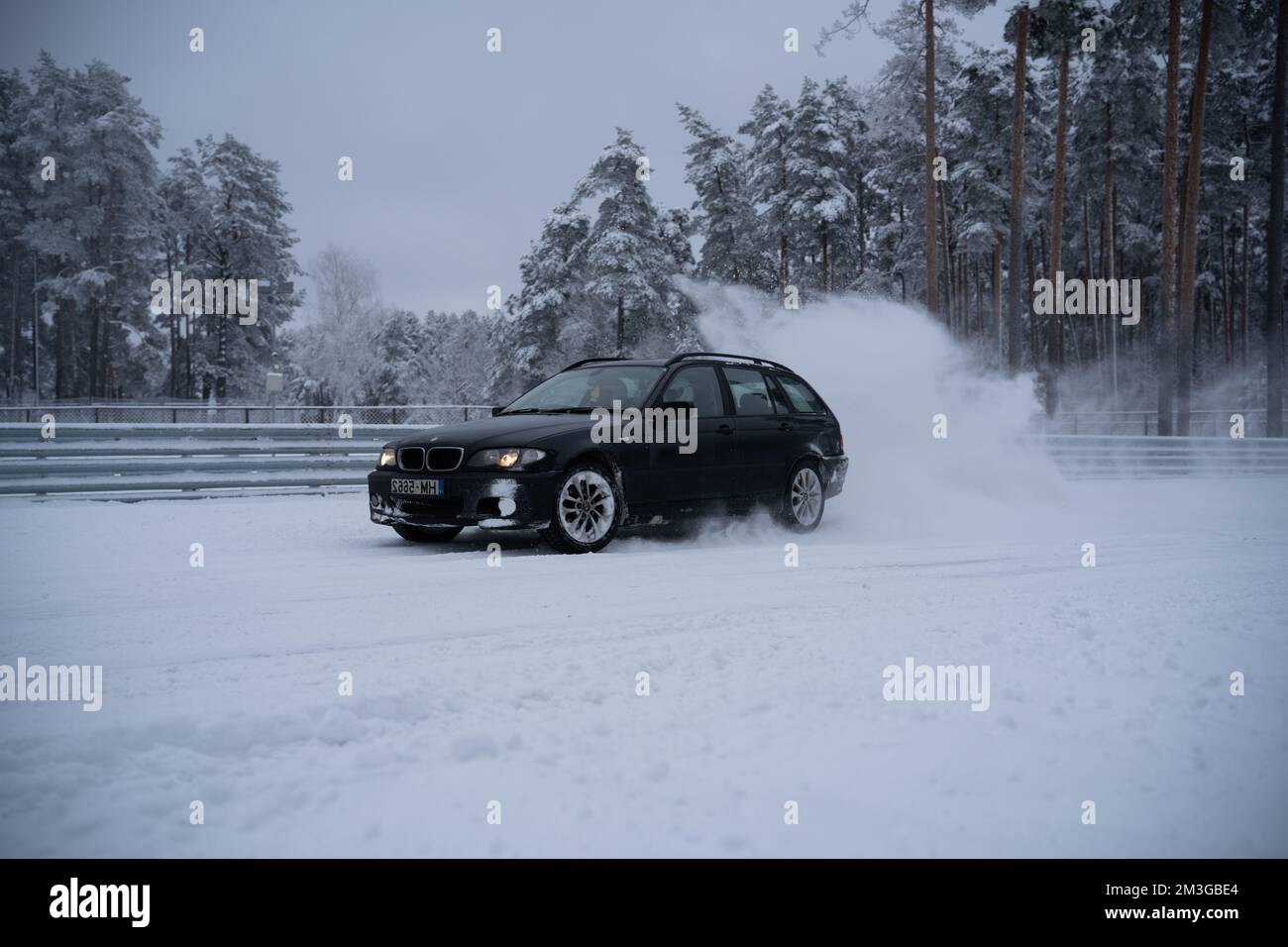 12-12-2022 Riga, Latvia  a car driving through a snow covered road in the middle of winter with trees in the background and a dusting of snow on the g Stock Photo