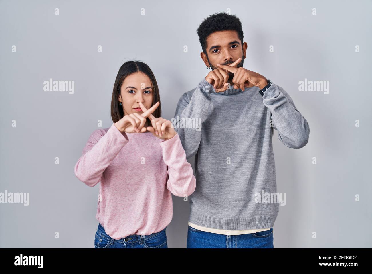 Young hispanic couple standing together rejection expression crossing ...