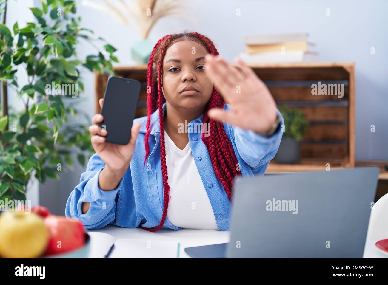 African american woman with braided hair holding smartphone showing ...