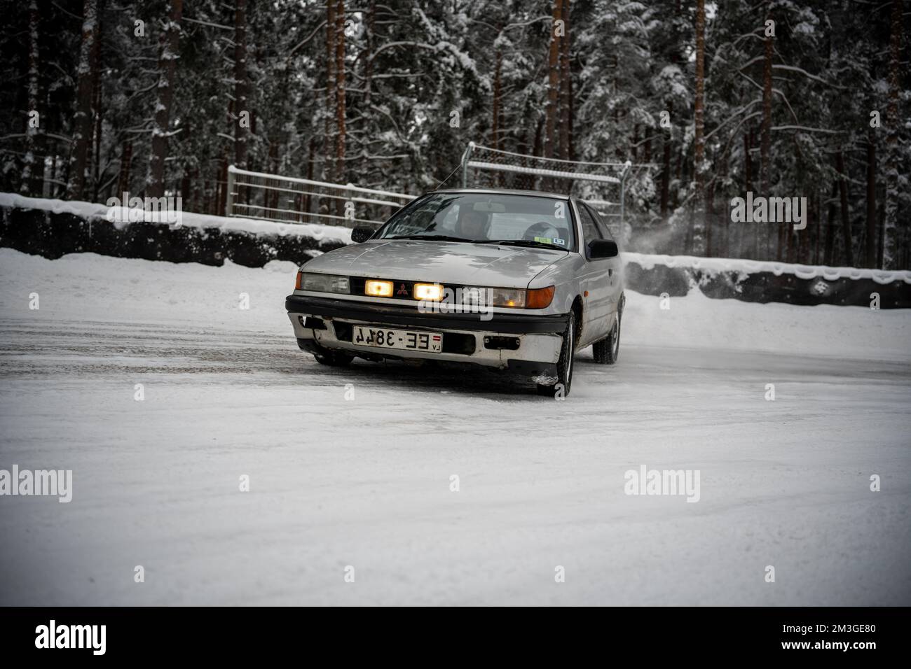 12-12-2022 Riga, Latvia  a car driving down a snowy road in the snow with trees in the background and snow on the ground. . Stock Photo