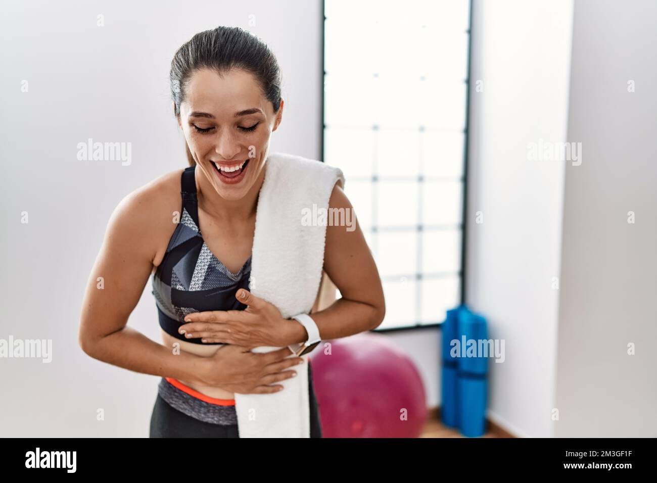 Young brunette woman wearing sportswear and towel at the gym smiling ...