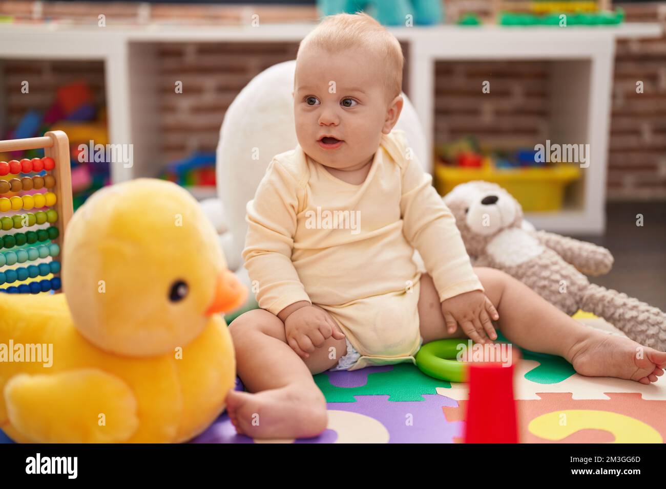 Adorable caucasian baby playing with hoops toy sitting on floor at ...
