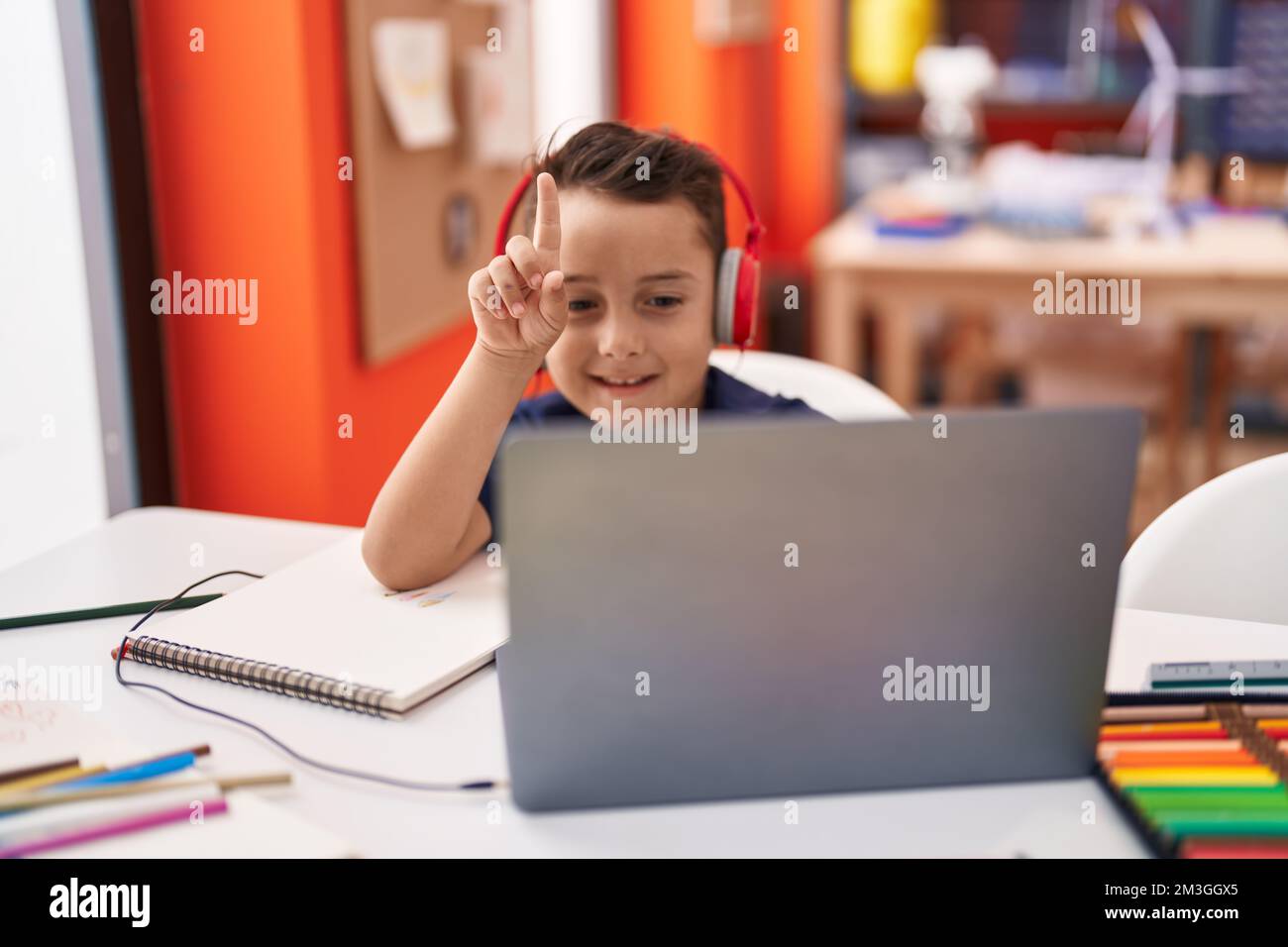 Adorable hispanic toddler student using laptop and headphones studying ...