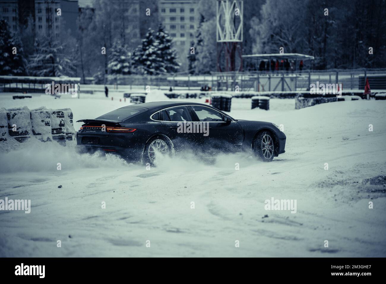 12-12-2022 Riga, Latvia  a car driving through a snow covered park in the wintertime with a city in the background and a building in the distance. . Stock Photo