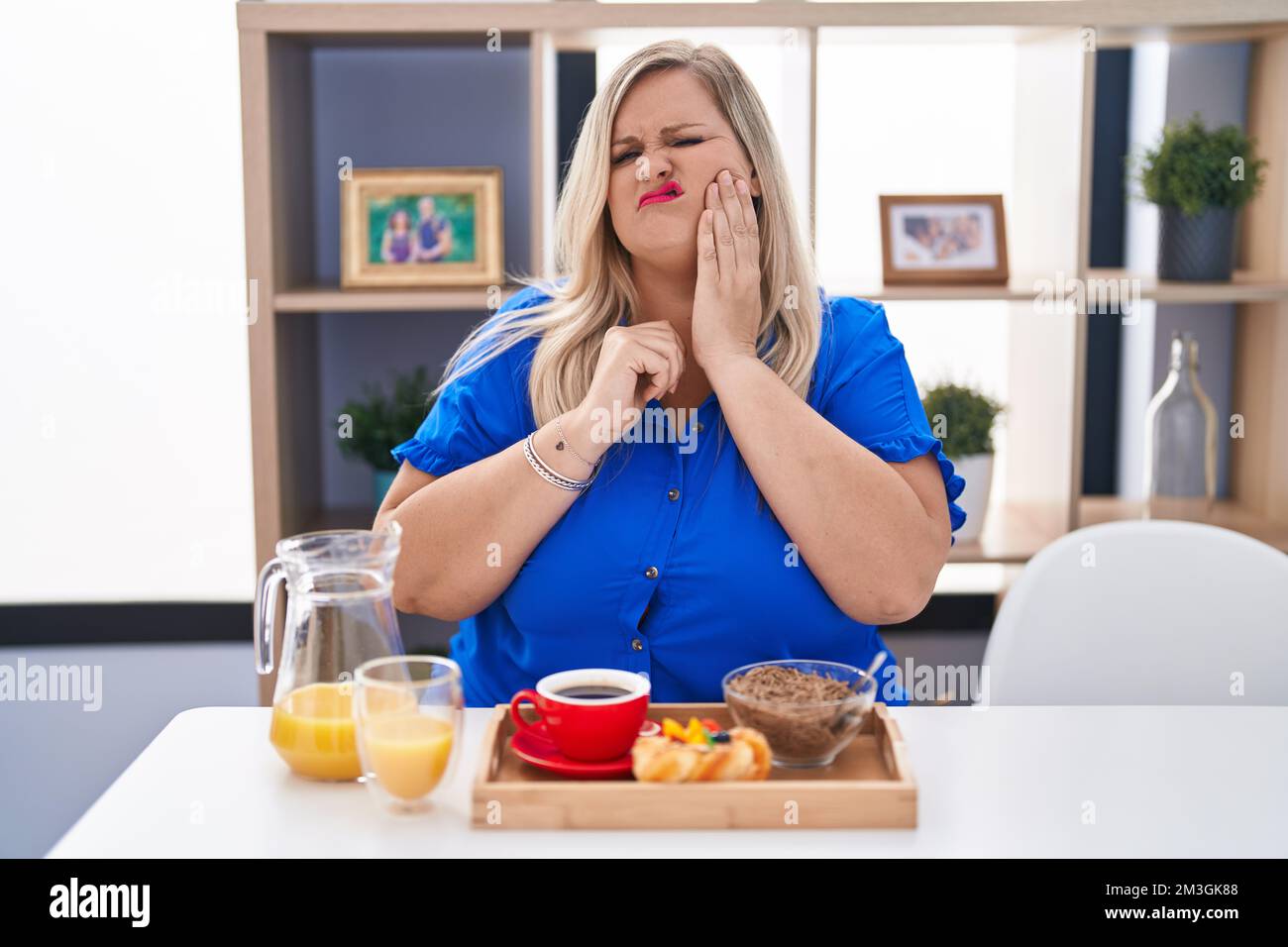 Caucasian plus size woman eating breakfast at home touching mouth with ...