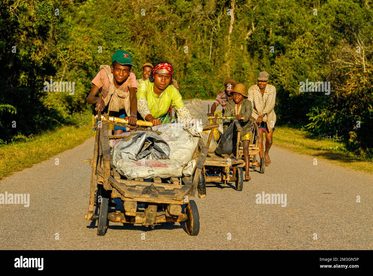Young boys pushing self made carts up the hill, along the road between Ranomafana and Antanarivo, Madagascar, Indian Ocean Stock Photo