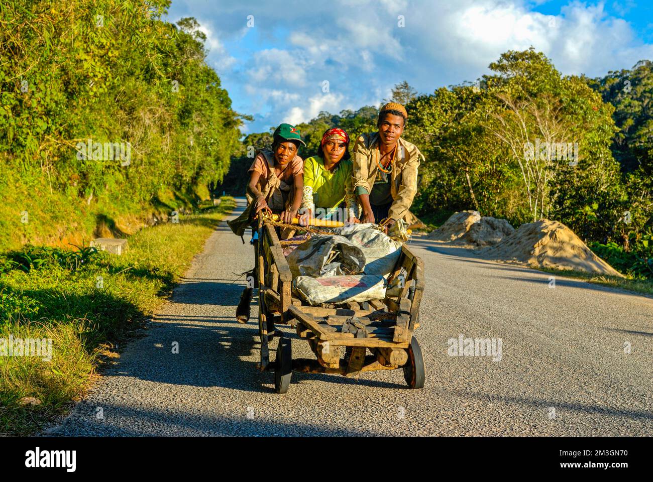 Young boys pushing self made carts up the hill, along the road between Ranomafana and Antanarivo, Madagascar, Indian Ocean Stock Photo