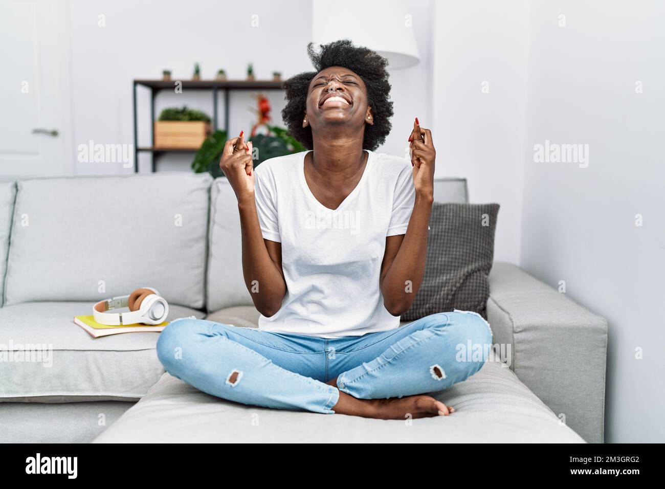 African young woman sitting on the sofa at home gesturing finger ...