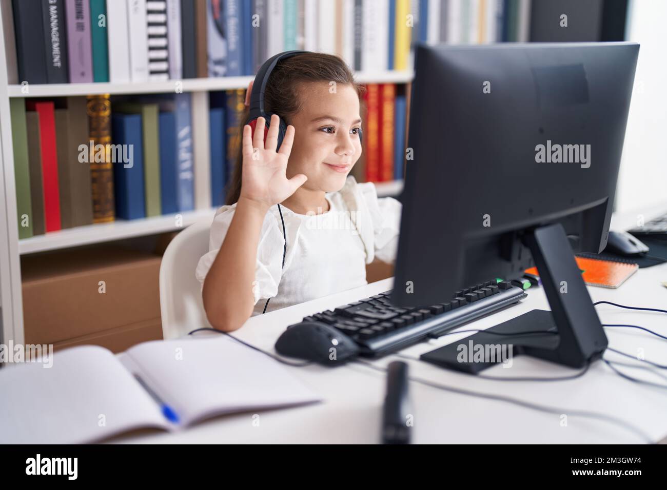 Adorable hispanic girl student using computer and headphones having ...