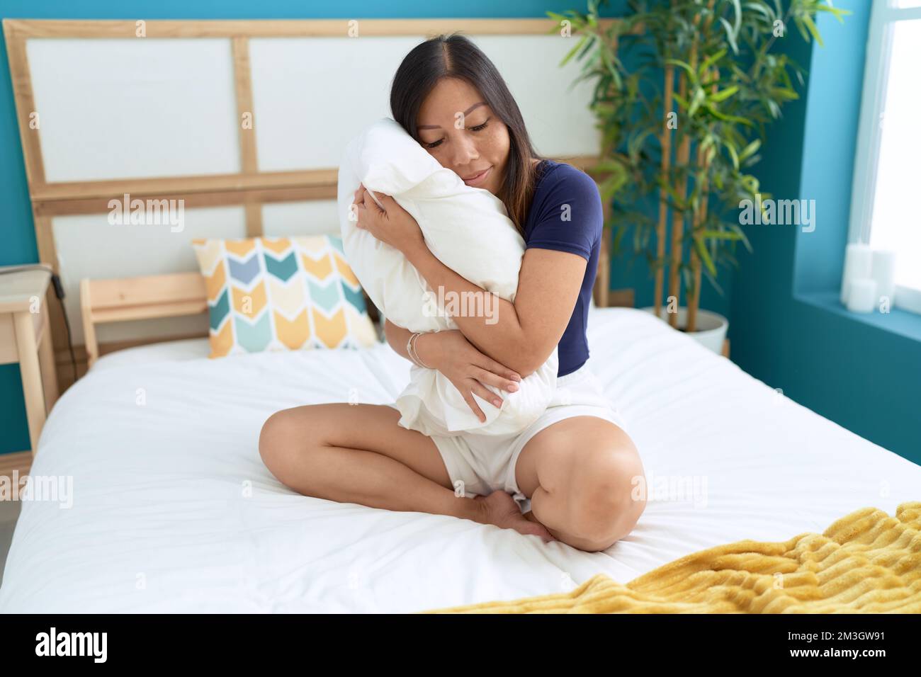 Young asian woman hugging pillow sitting on bed at bedroom Stock Photo