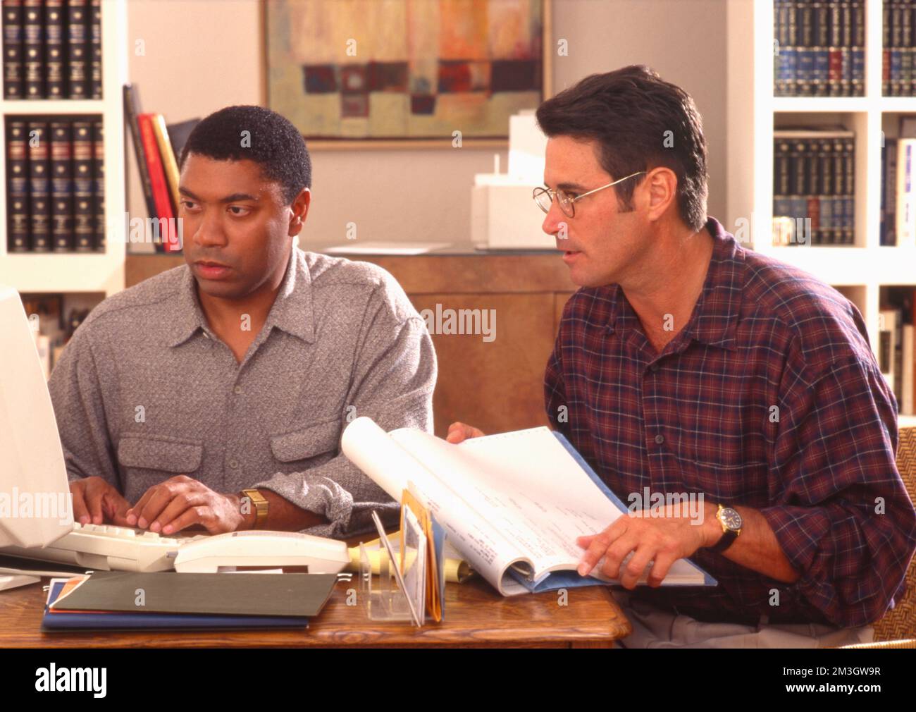 Two younger men working on a computer in home office Stock Photo