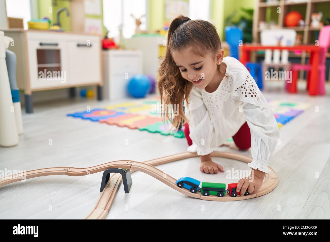 Adorable hispanic girl playing with cars toy sitting on floor at ...