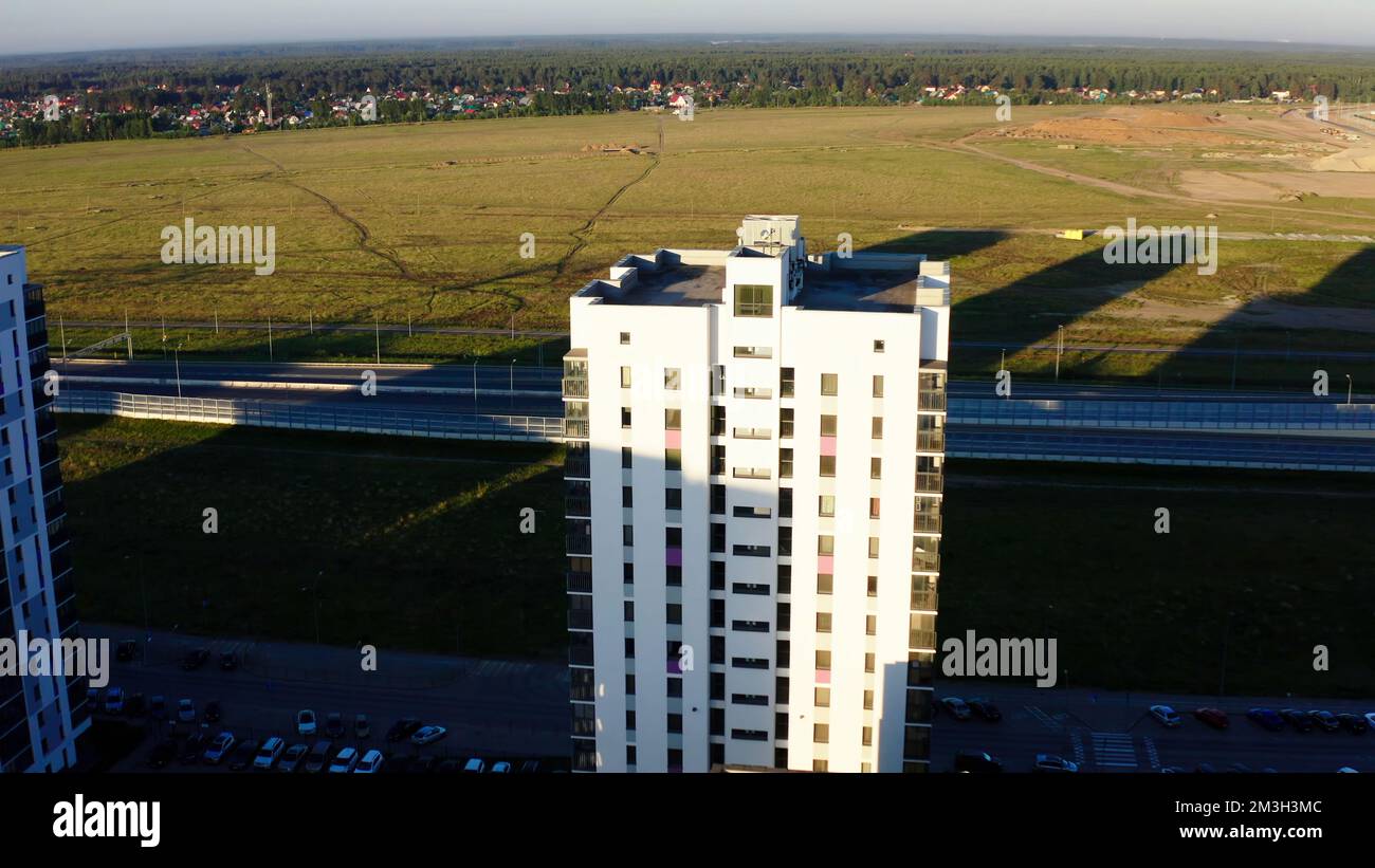 Drone view of the new area. Stock footage.Huge residential 30-storey houses with drawings and beautiful green fields next to the road for transport. H Stock Photo