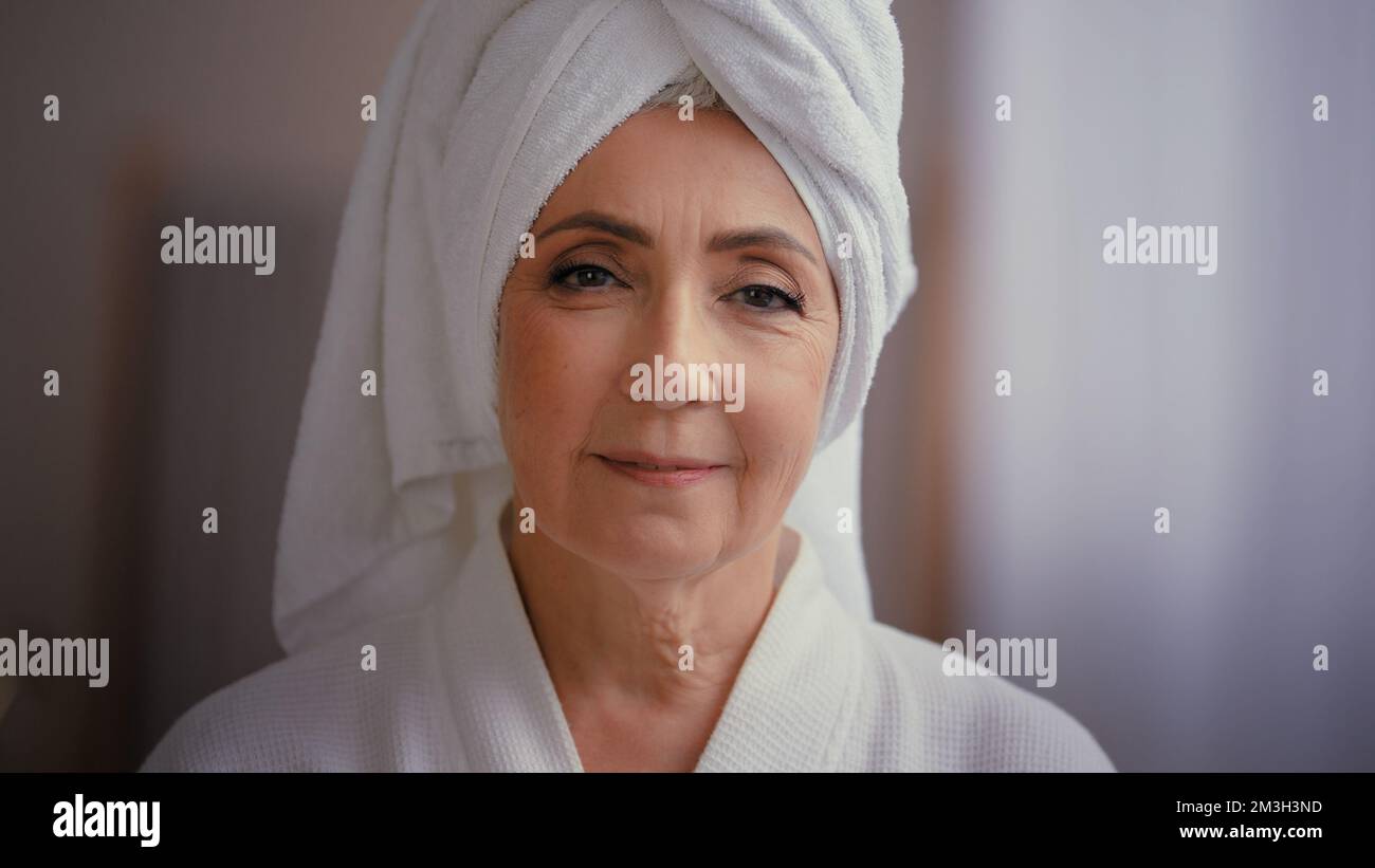 Caucasian old senior mature attractive middle-aged woman 60s lady 50s female model wearing bathrobe and white towel on head with wrinkled face looking Stock Photo