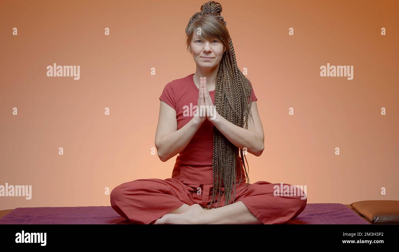 A meditating girl. Action.A young girl with afro-curls is sitting on a rug and doing yoga. High quality 4k footage Stock Photo