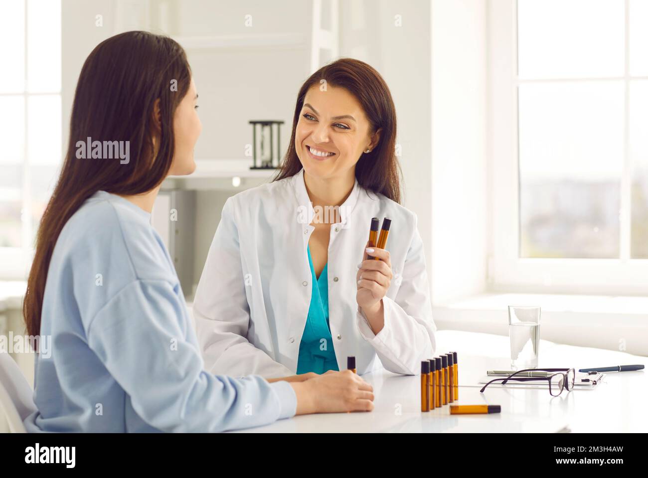 Friendly smart woman doctor tells her patient about benefits of essential oils in treatment. Stock Photo