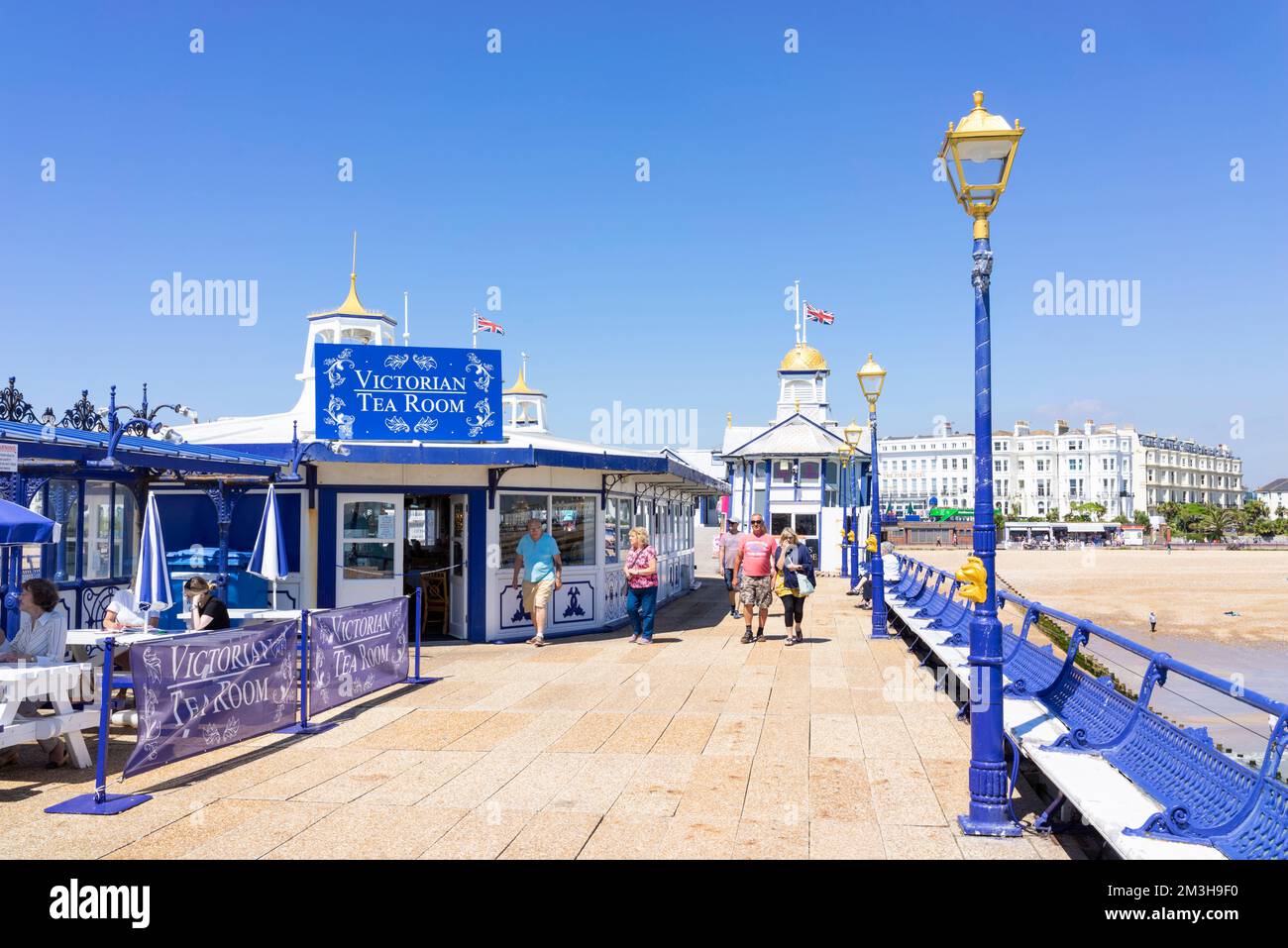 Eastbourne East Sussex Looking back along the pier towards People sat at cafe tables on Eastbourne Pier Eastbourne East Sussex England UK GB Europe Stock Photo