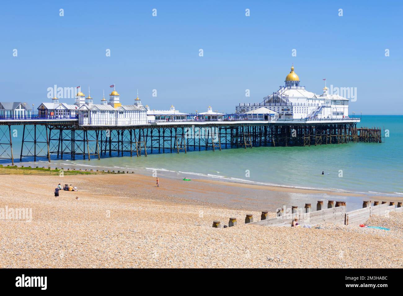 Eastbourne East Sussex Eastbourne beach and Eastbourne pier with people on the beach sunbathing Eastbourne beach Eastbourne East Sussex England UK GB Stock Photo