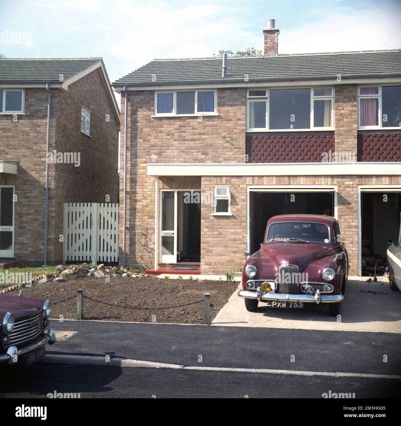 cira late 1960s, historical, a post-war maroon coloured Humber Hawk car parked in the driveway of a new semi-detached house, with an internal garage, built in the modern style of the era, as seen on many housing estates in Britain at this time. The Humber Hawk was a car built in Britiain by Humber Limited, between 1945 and 1967, with a number of different styles and variations. The car seen here is most likley the Humber Hawk Mark VI which was introduced in 1954 an upgraded version of the post-war 1948 Hawk, a completely newly designed car than the first and original 1945 Hawk. Stock Photo