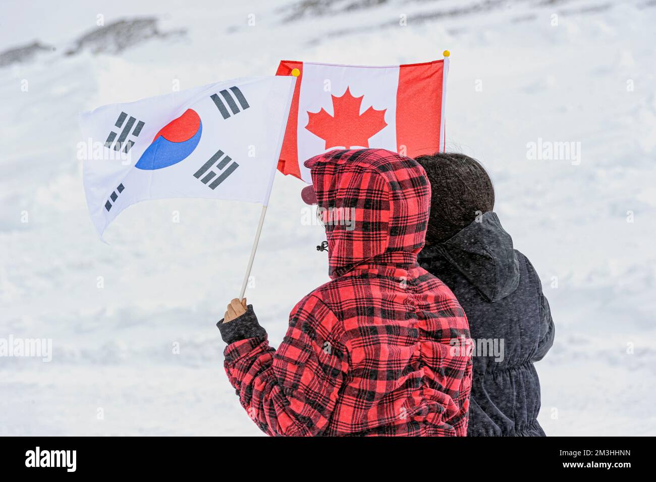 Two tourists holding Japanese and Canadian flags on a winter mountain in Canada Stock Photo