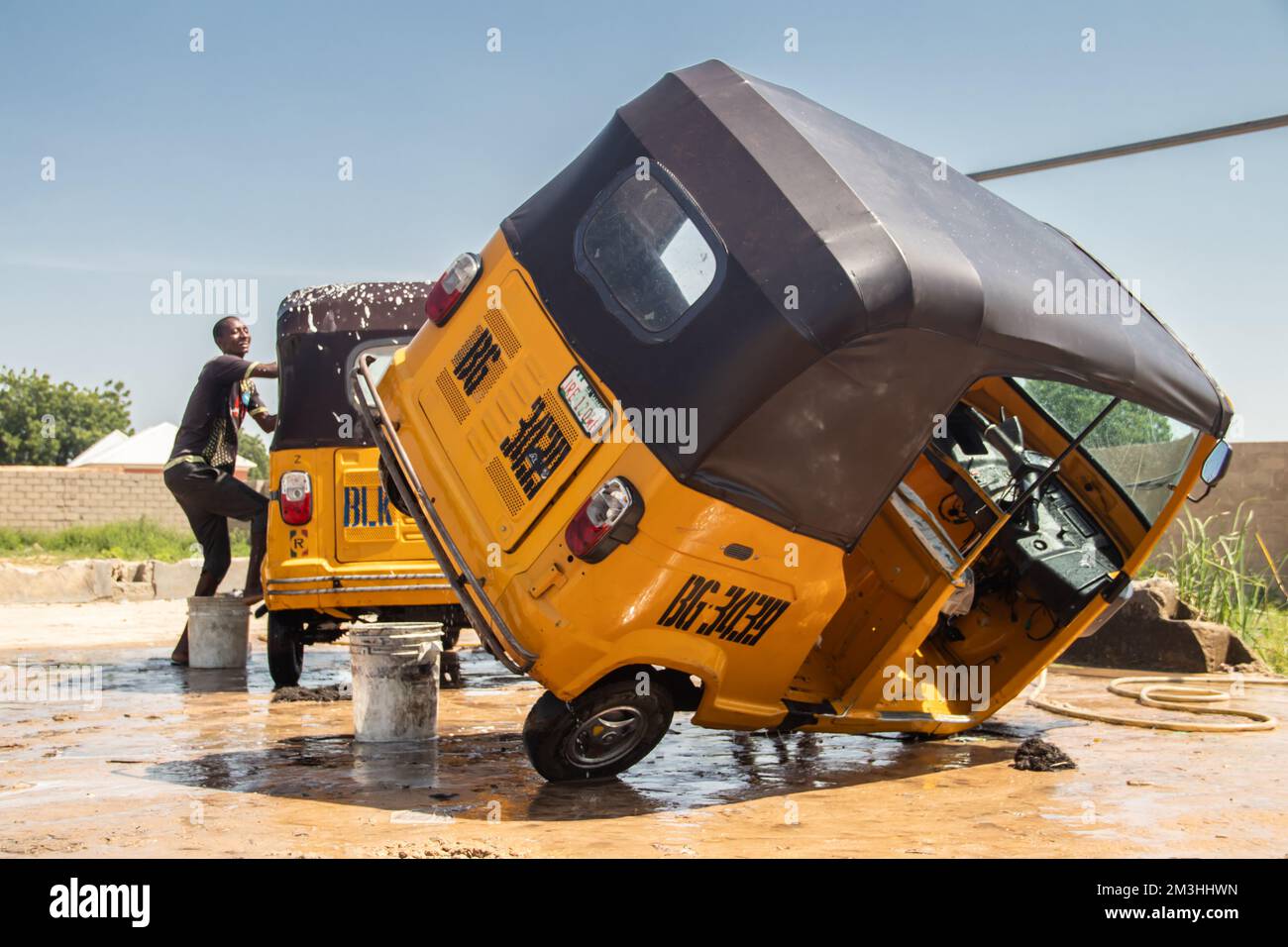 Car wash service in Africa, young boys working hard and cleaning local taxi (tuktuk Stock Photo