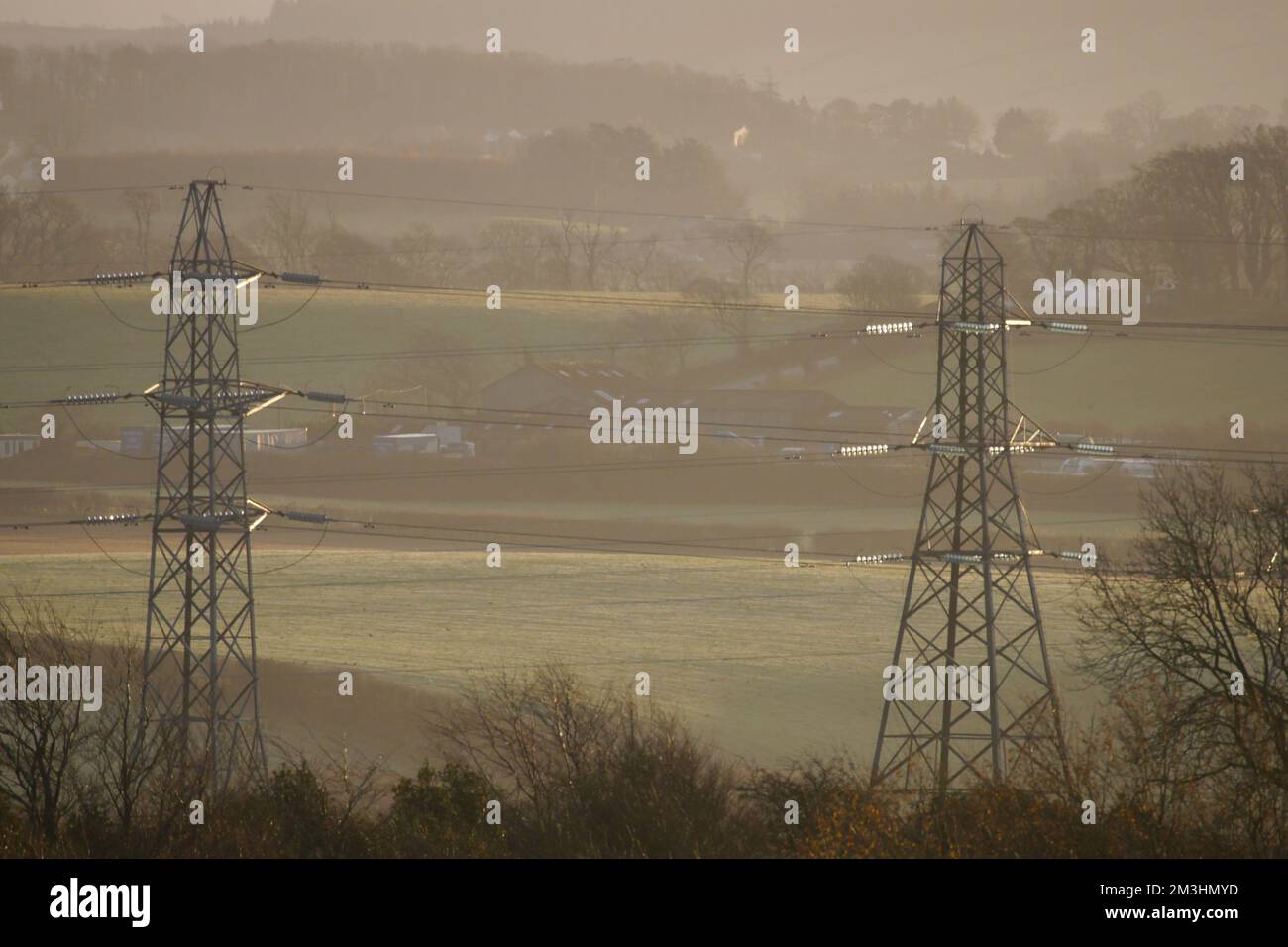 Electrical Power Pylons, lit by the setting Sun, Dearham, Cumbria, England, United Kingdom Stock Photo