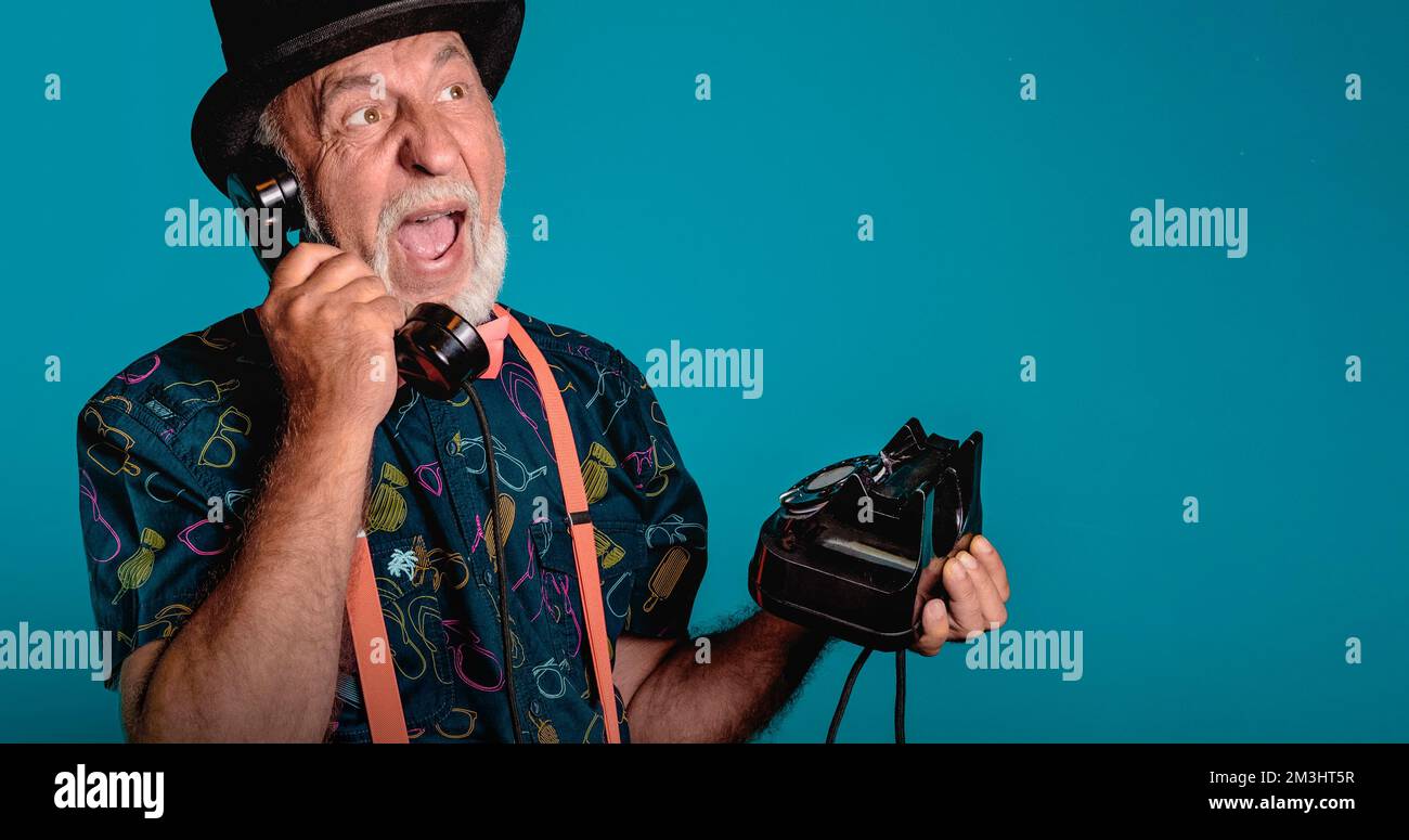 Emotional conversation on the phone. Banner with an elderly man on a blue background. Creative look. copy space Stock Photo