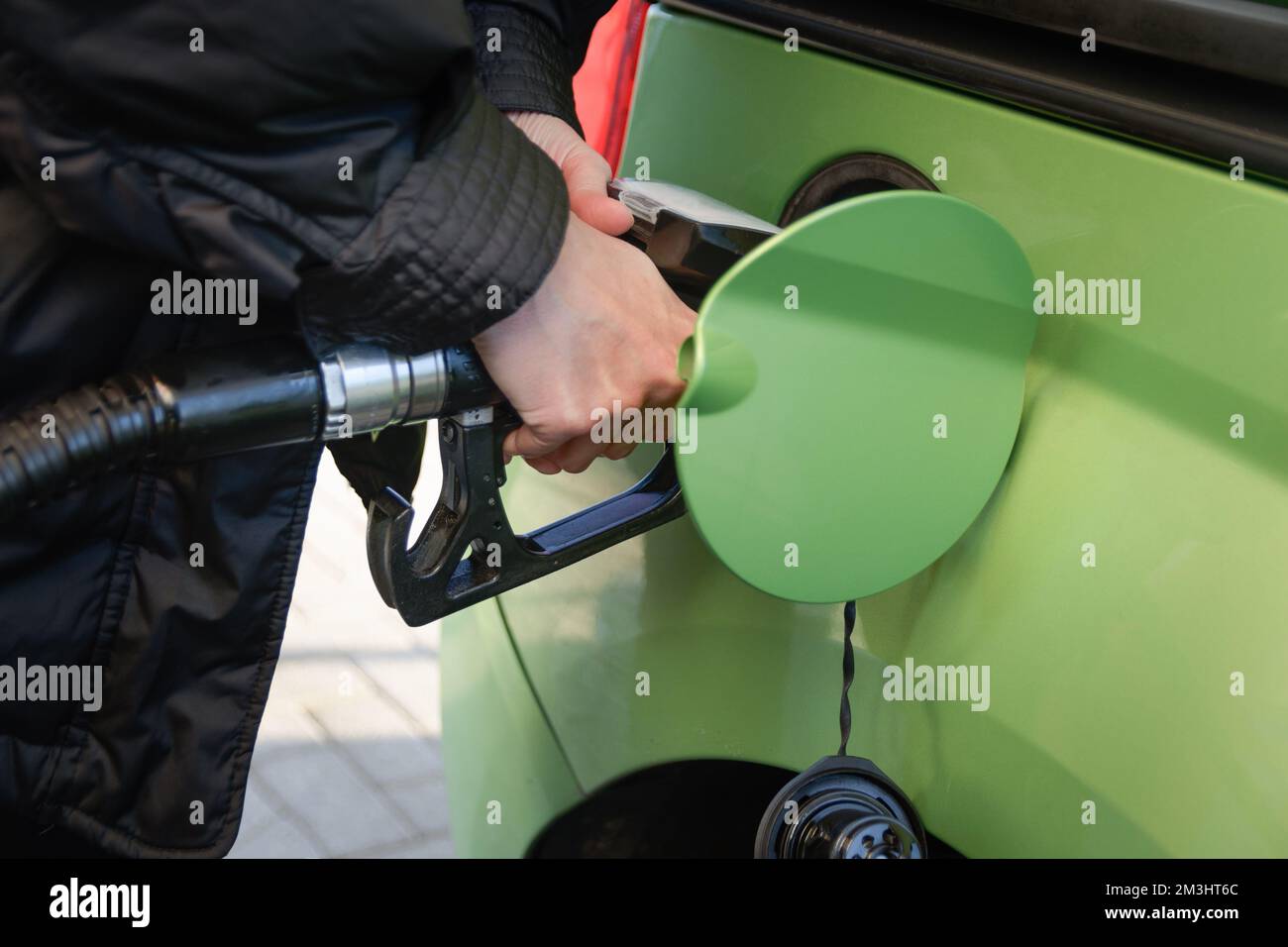 Filling up the car. In a gas station, a woman fills her gas tank Stock Photo