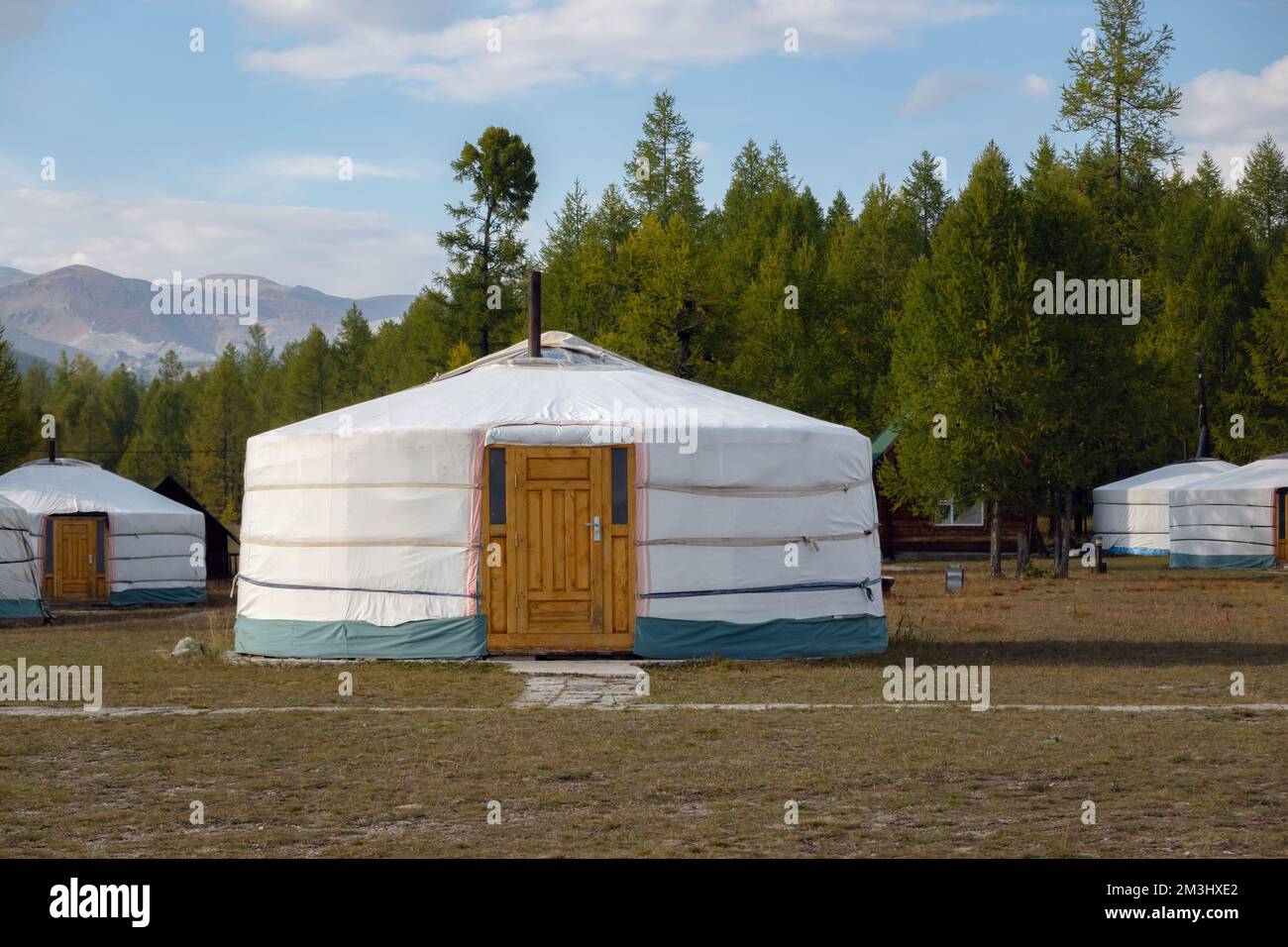 Yurt camp on a beautiful sunny day in Mongolia. Ger campsite in rural country, nature in the background. Stock Photo