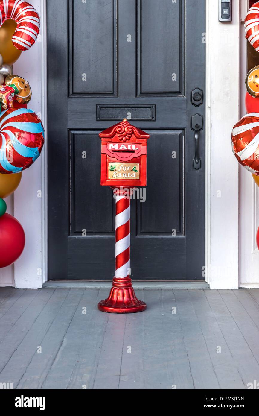 Decorative Christmas Santa Claus mailbox for letters from children outside a black exterior door with balloons Stock Photo